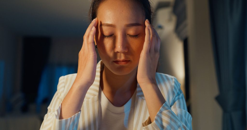 Close-up photo of an asian woman having a headache.